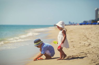 Çocuklar yaz plajında kumla oynarlar.