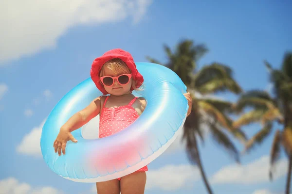 Ładna dziewczynka z zabawka pływająca ring na tropikalnej plaży — Zdjęcie stockowe