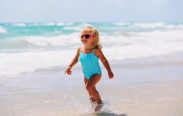 Meisje lopen spelen met golven op het strand — Stockfoto