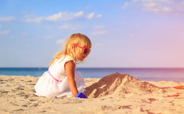 Söt liten flicka leker med sand på stranden — Stockfoto