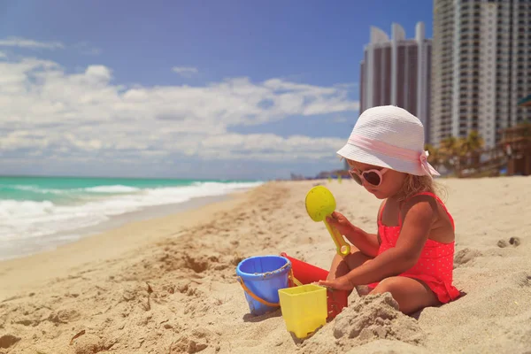 Klein meisje spelen met zand op het strand — Stockfoto