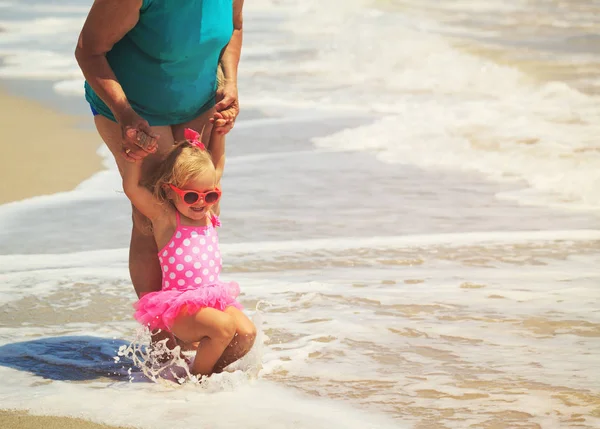 Grootmoeder en meisje spelen met golven op het strand — Stockfoto