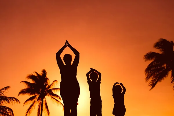 Siluetas familiares haciendo yoga — Foto de Stock