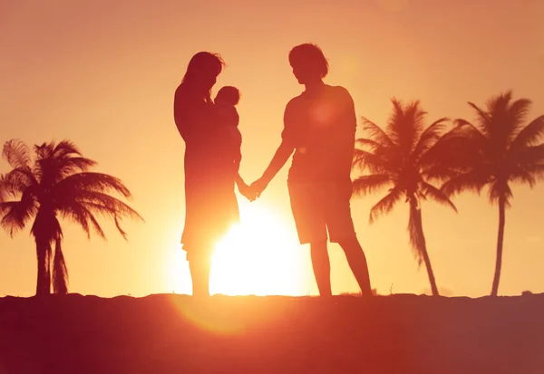 Glückliches Liebespaar mit kleinem Baby Händchen haltend am Sonnenuntergang Strand — Stockfoto
