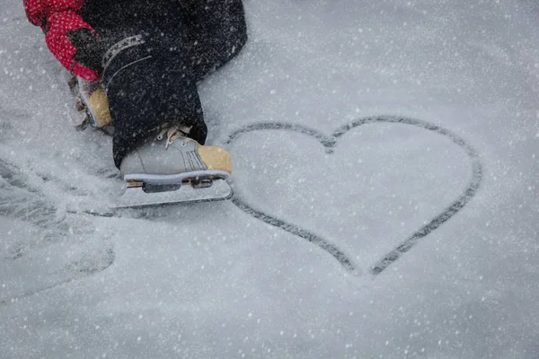 De voeten van het kind in het schaatsen en hart op sneeuw — Stockfoto