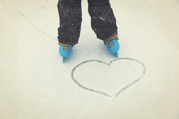 De voeten van het kind in het schaatsen en hart op sneeuw — Stockfoto