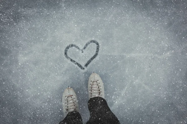 Voeten in het schaatsen en hart op sneeuw — Stockfoto