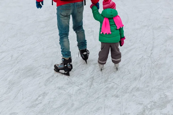 Отец и маленькая дочь ноги учатся кататься на коньках зимой — стоковое фото