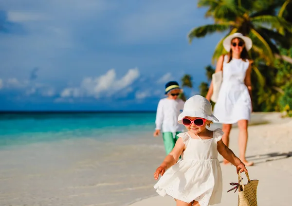 Schattig klein meisje lopen op strand met familie — Stockfoto