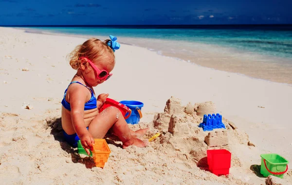 Schattig meisje spelen met zand op het strand — Stockfoto