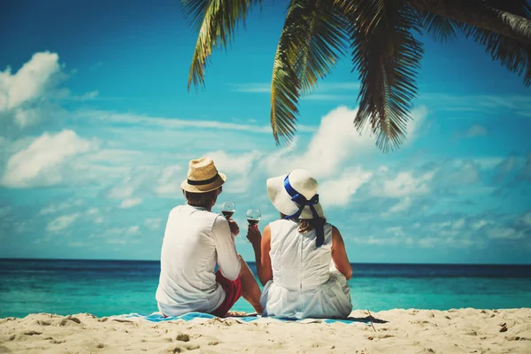 Счастливая любящая пара пьет вино на тропическом пляже — стоковое фото