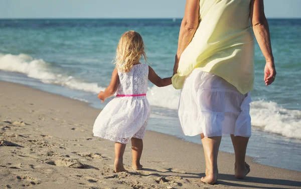 Gelukkig grootmoeder met meisje lopen op strand — Stockfoto