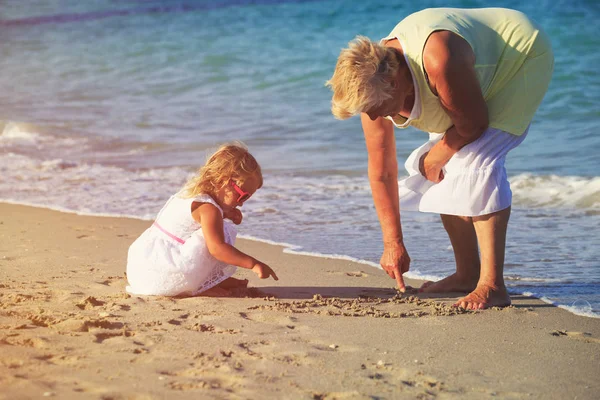 Oma met kleine meisje spelen op strand — Stockfoto