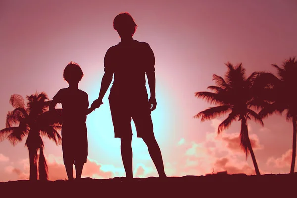 Silhouet van vader en zoon hand in hand bij zonsondergang strand — Stockfoto