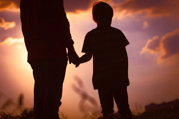 Silhouette von Vater und Sohn beim Händchenhalten bei Sonnenuntergang — Stockfoto