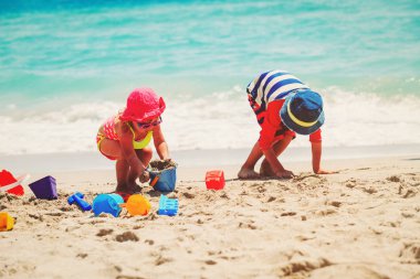 Çocuklar yaz plajında kumla oynarlar.