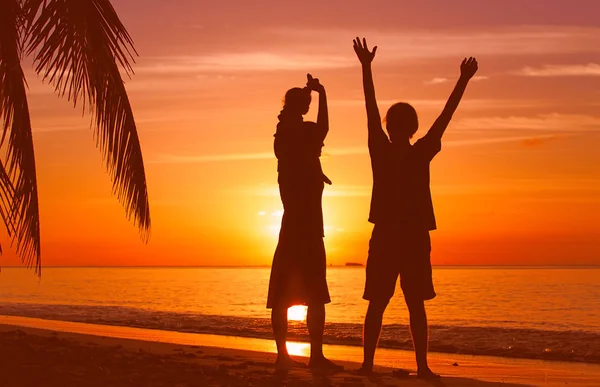 Coppia felice con bambino alla spiaggia del tramonto — Foto Stock