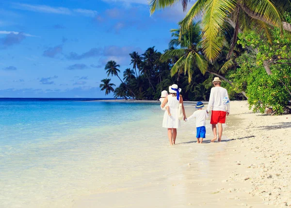 Familia joven con dos niños caminando en la playa tropical —  Fotos de Stock