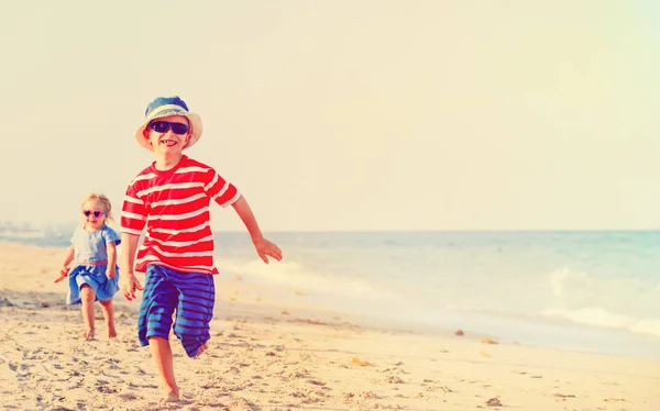 Gelukkig weinig jongen en meisje lopen op zand strand — Stockfoto