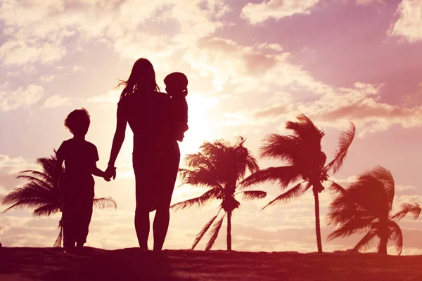 Mãe e dois filhos caminhando na praia do pôr do sol — Fotografia de Stock