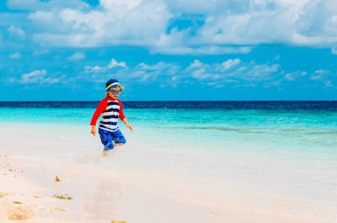 tropik sahilde sıçramasına su çalışan mutlu küçük çocuk