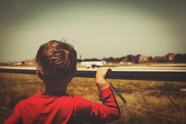 Liten pojke tittar på flygplan som lyfter på flygplatsen — Stockfoto