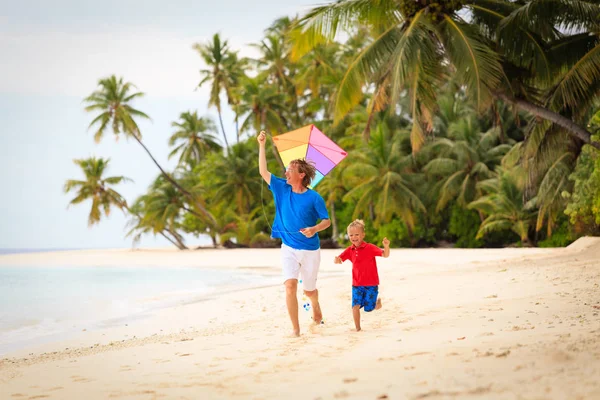 Padre e hijo pequeño volando cometa en la playa —  Fotos de Stock