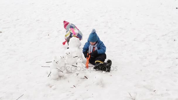 Kleine jongen en meisje sneeuwpop bouwen in de winter — Stockvideo