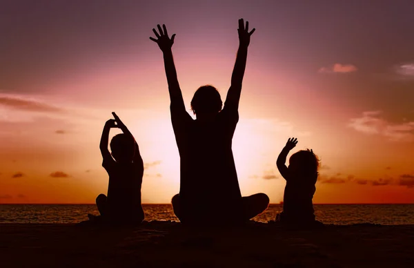 Силуэт счастливого отца и детей на закатном пляже — стоковое фото