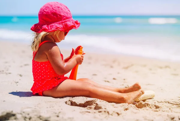 Защита от солнца - маленькая девочка с солнцезащитным кремом на пляже — стоковое фото