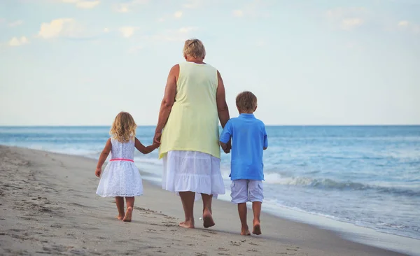 Avó feliz com filhos- menino e menina- na praia — Fotografia de Stock