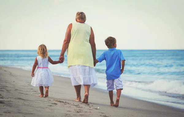 Glad mormor med kids - liten pojke och flicka-vid stranden — Stockfoto