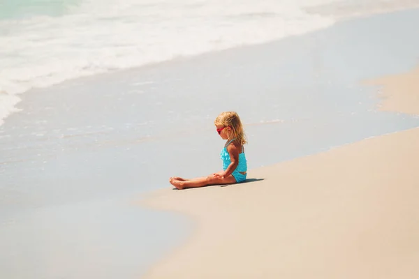 Kleines Mädchen spielt mit Wasser am Strand — Stockfoto