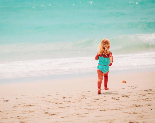 Маленькая девочка бегать играть с волнами на пляже — стоковое фото