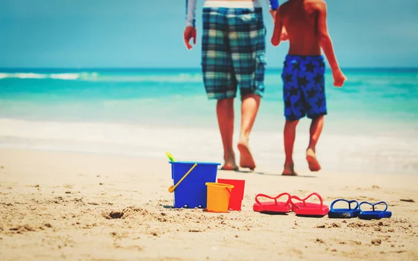 Vader en zoon gaan zwemmen op strand — Stockfoto