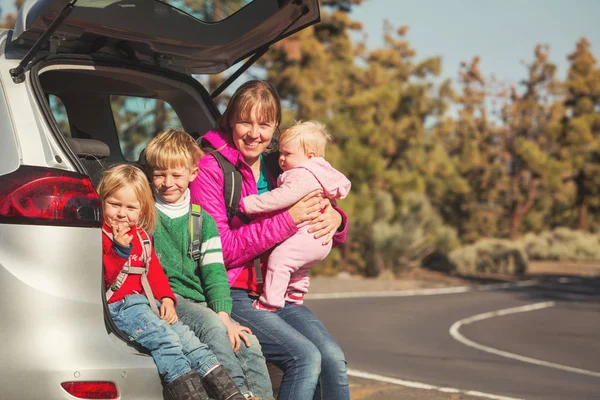 Happy mother with tree kids travel by car on road — Stock Photo, Image