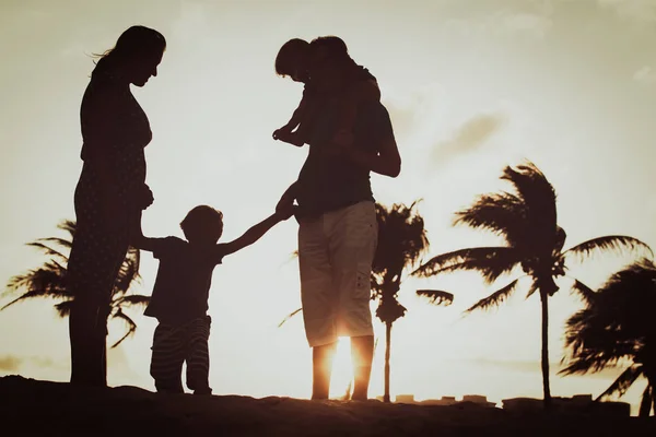 Familia feliz con dos niños en la playa del atardecer — Foto de Stock