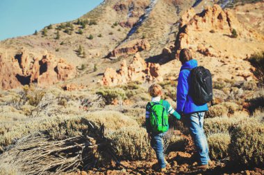 Baba ve oğul dağlarda yürüyüş yapıyor.