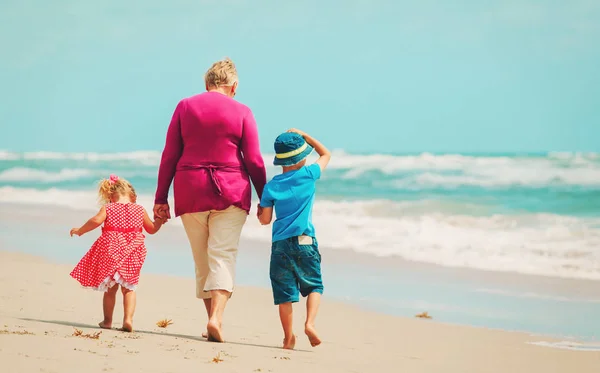 Счастливая бабушка с детьми маленький мальчик и девочка на пляже — стоковое фото