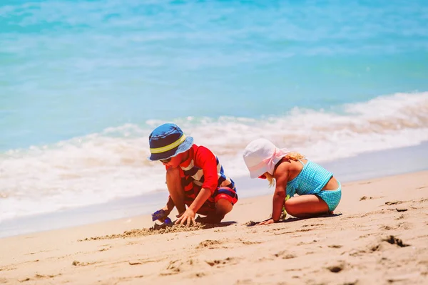 Liten pojke och flicka leka med sand på stranden — Stockfoto