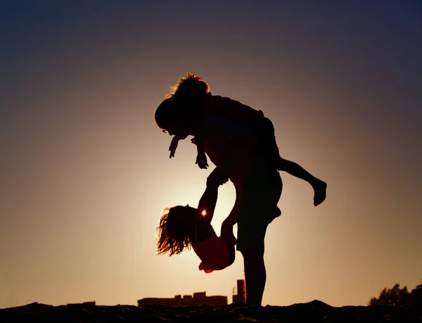 夕焼け空で遊ぶ 2 人の子供を持つ父のシルエット — ストック写真