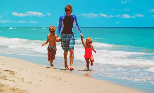 पिता और दो बच्चे समुद्र तट पर चल रहे हैं — स्टॉक फ़ोटो, इमेज
