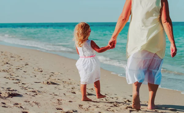 Grootmoeder met meisje lopen op strand — Stockfoto