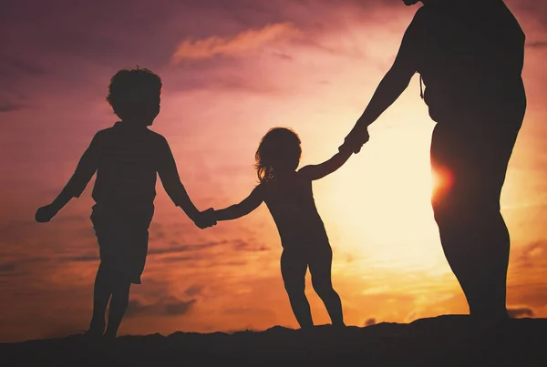 Silhouette di famiglia con bambini giocare al tramonto spiaggia — Foto Stock