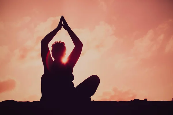 Silhouettes de femme âgée faisant du yoga au coucher du soleil ciel — Photo