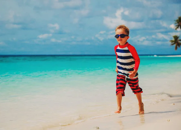 Mały chłopiec uruchomić rozpryskujących na plaży — Zdjęcie stockowe