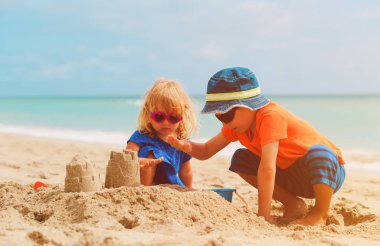 Küçük erkek ve kız yaz sahilde kum ile oynamak