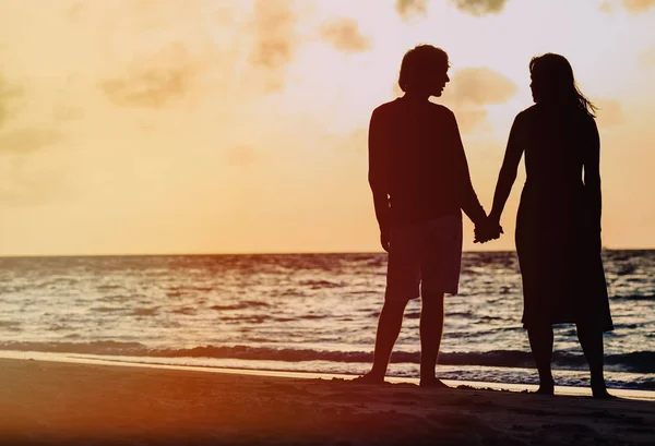 Couple romantique tenant la main à la plage du coucher du soleil — Photo