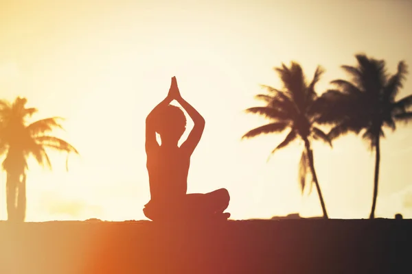 Silueta de niño haciendo yoga al atardecer playa — Foto de Stock