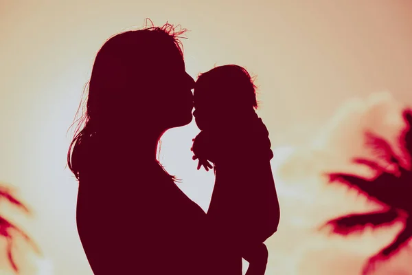 Amorevole madre e baciare il piccolo bambino giocare al tramonto — Foto Stock